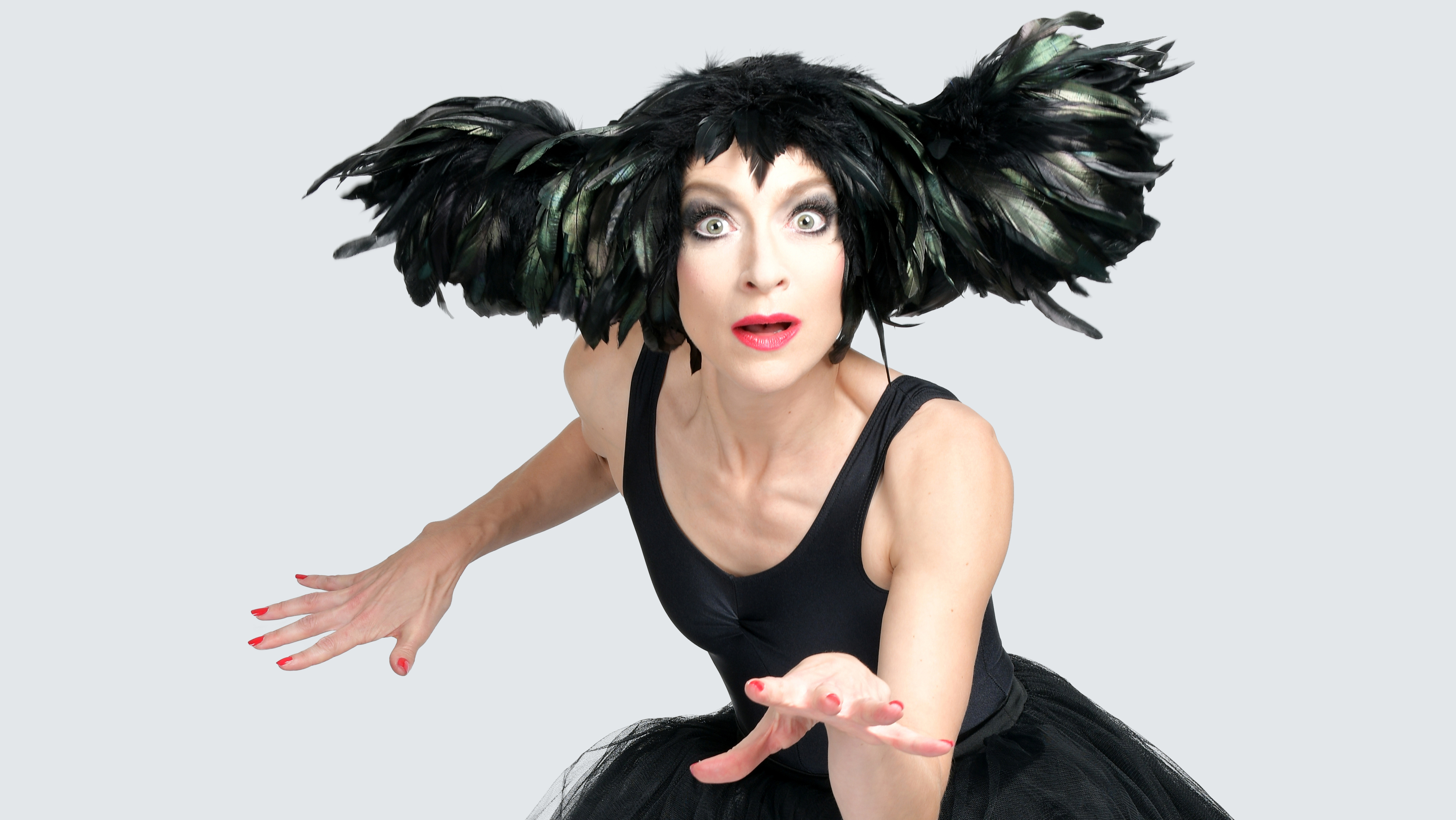Image of woman wearing a black dress and a large black headpiece made out of feathers