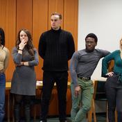Five people stand together in a line watching on into the distance.