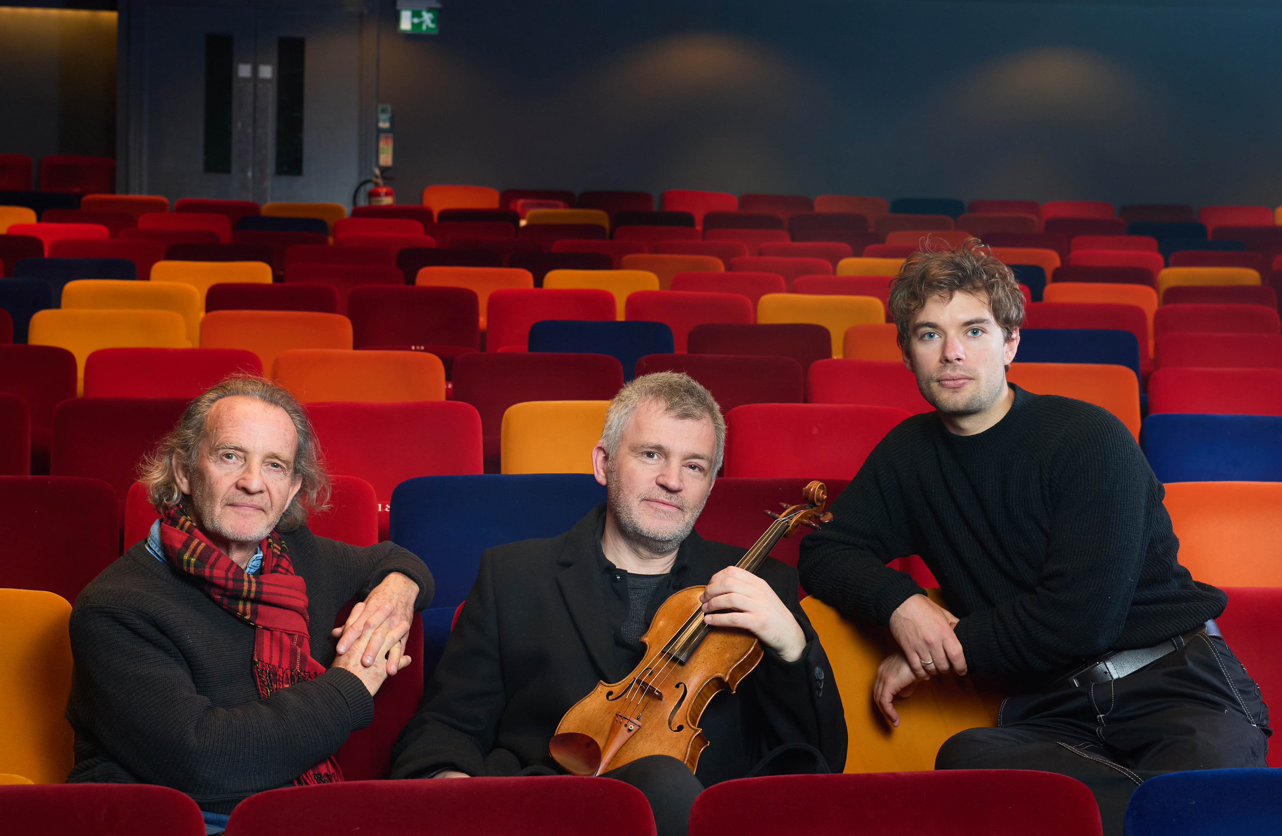 Anton Lesser, David Le Page and Charlie Hamblett sat in the Oxford Playhouse auditorium. David sits in the middle of the two actors holding a violin.