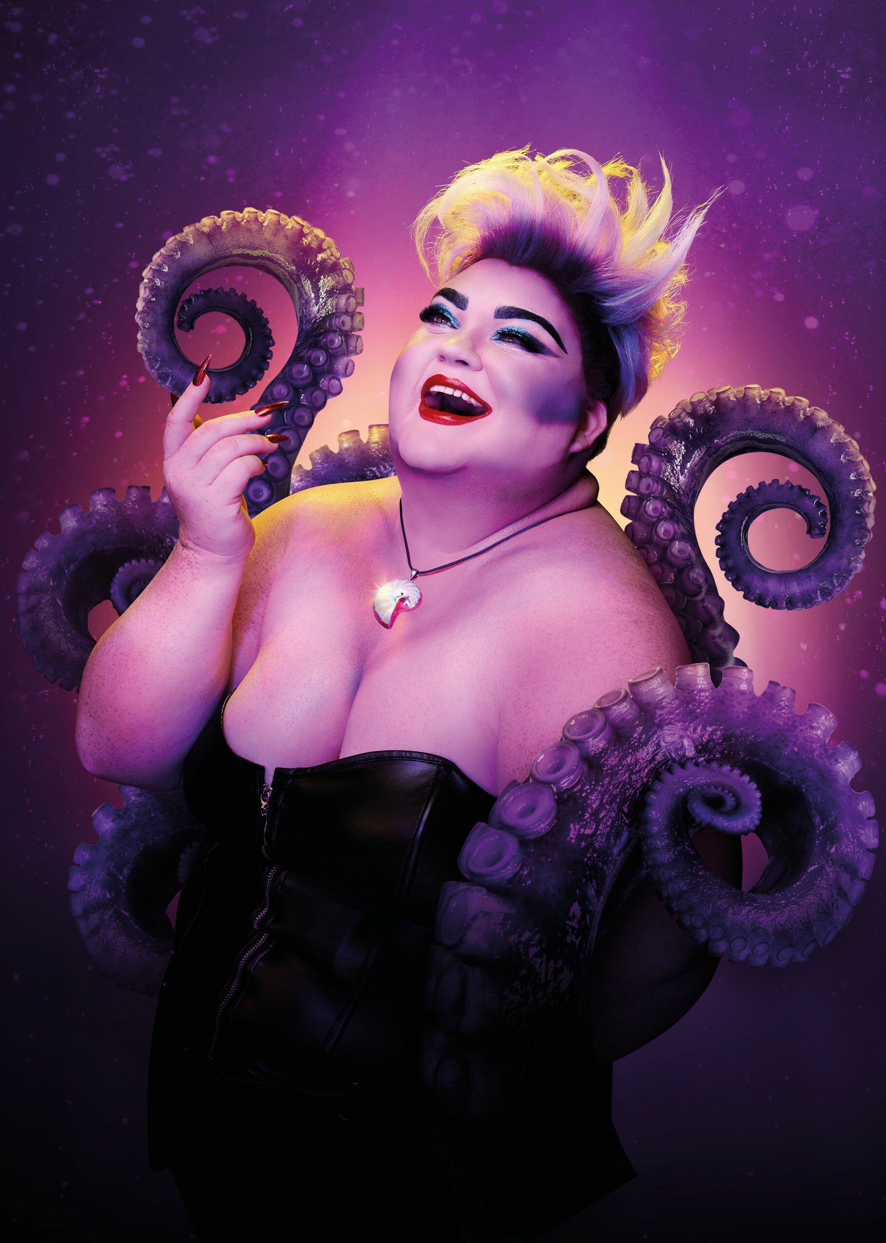 An illustration of Ursula with four tentacles surrounding her. She holds one hand up and smiles with her mouth open.