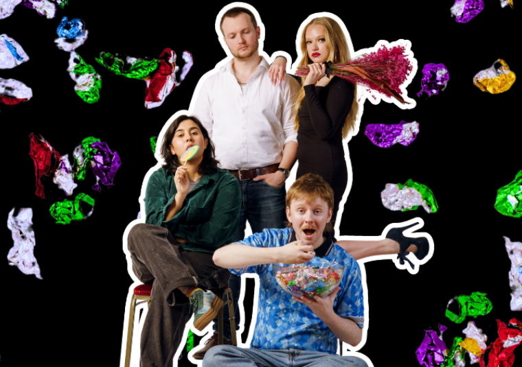A man in a white top, a woman in a black dress and heels holding a bundle of dried flowers, a woman sat on a chair wearing a button up and brown trousers with a lolly, and a man in a bright blue polo shirt eating lollies from a glass bowl stand in front of a background of brightly wrapped lollies falling behind.