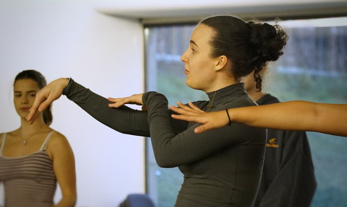 A person holds two arms out in front of them, an image of their side profile looking to the left.
