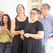 A group of actors looking attentively towards the other group of actors behind the camera. Some actors are smiling, others have soft expressions on their faces.