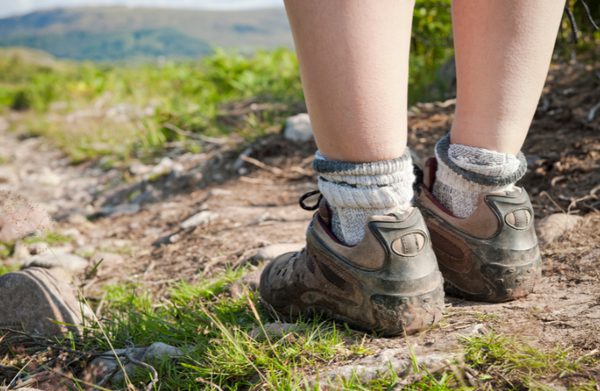 A child in hiking boots walking along a trail.