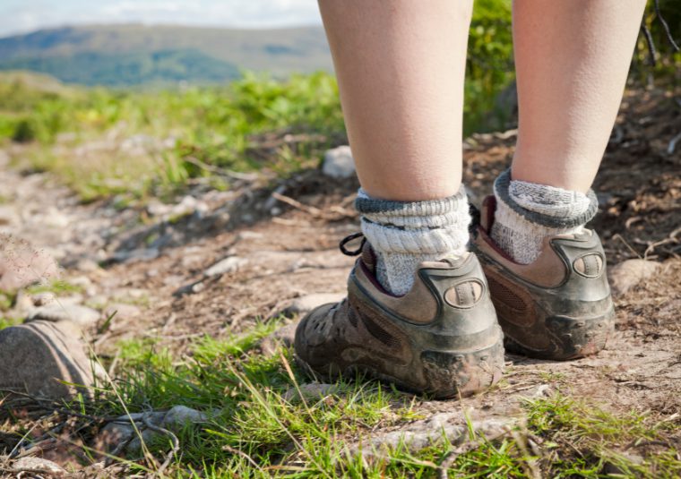A child in hiking boots walking along a trail.