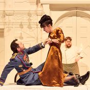Theseus and Hippolyta in a dramatic scene on top of the feasting table, with Hippolyta holding a knife towards Theseus.