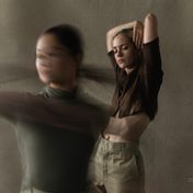 Dancer in muted green top and brown trousers in a modern dance pose.
