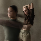 Dancer in muted green top and brown trousers in a modern dance pose.
