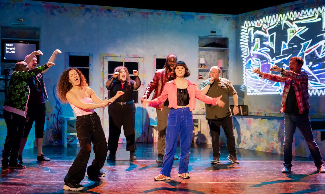 A group of actors singing passionately on stage all together.