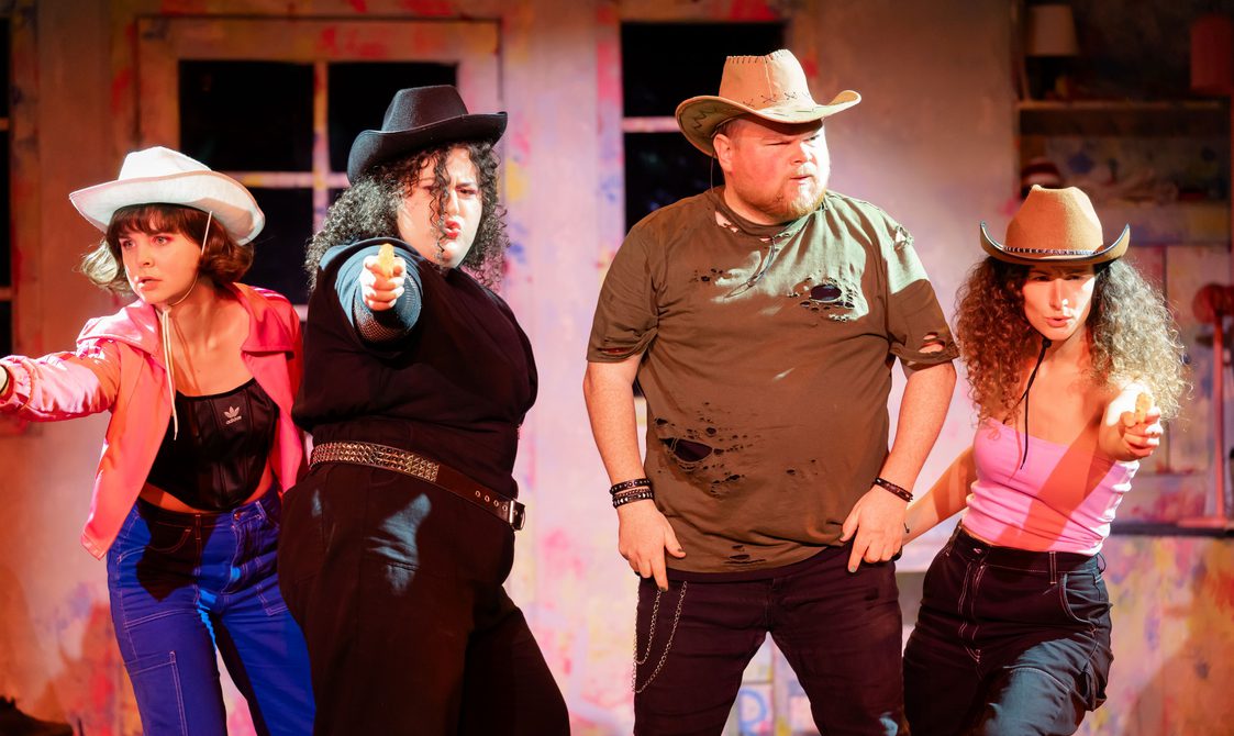 Actors in cowboy hats wielding pretend pistols with serious and funny expressions.