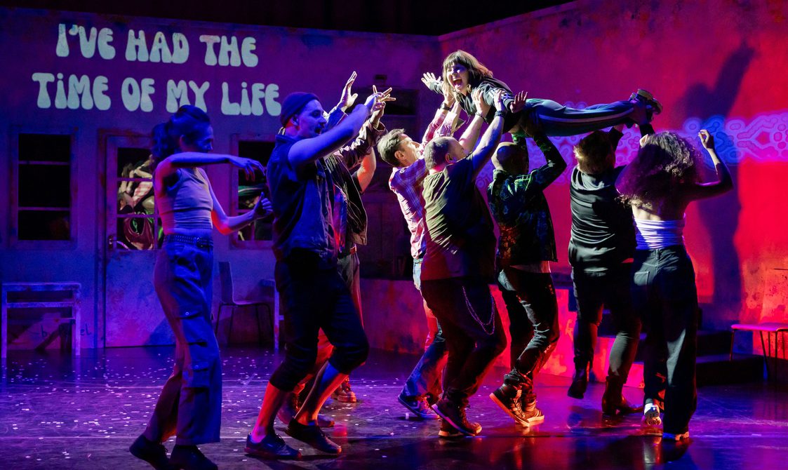 An actor being lifted up recreating the Dirty Dancing scene with the projection of 'I've had the time of my life' in the background.