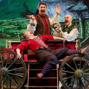 Lying on a cart on stage, someone is being tormented by a spider and a skull. They are dressed in tudor costume and the spider and skull are props held over them by two other actors in costume, gestures and faces dramatic.