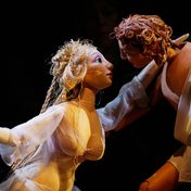 Venus leans in to kiss Adonis, they are wood and fabric puppets, intricate and articulated. Puppeteers and strings are not visible.