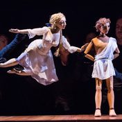 Venus flies to touch Adonis's arm where he's stood in contemplation. They are wood and fabric puppets, puppeteers barely visible in black gloves.