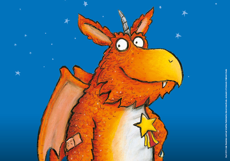 Zog the dragon is pictured with a star badge and elbow plaster, smiling, in an illustration from the story.