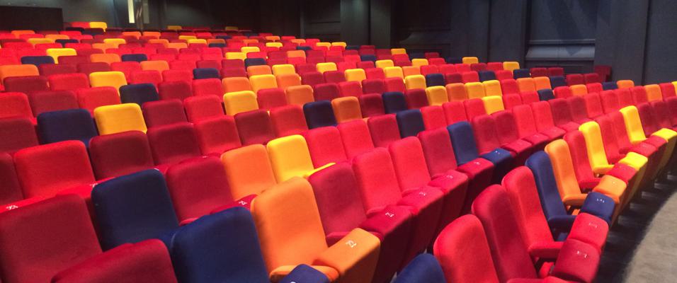 A close up shot of rows of seats in OP's auditorium. They are red, orange, purple and yellow.