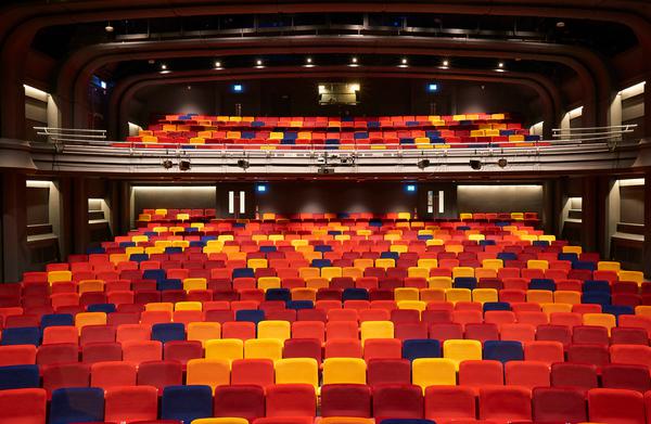 A wide shot of OP's auditorium. There are seats in red, orange, purple and yellow.
