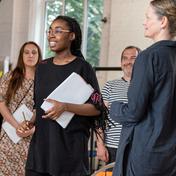 The cast of The Mirror Crack'd stand in a rehearsal studio holding scripts.