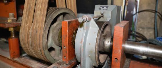 Two grey cogs, one with a belt around it.