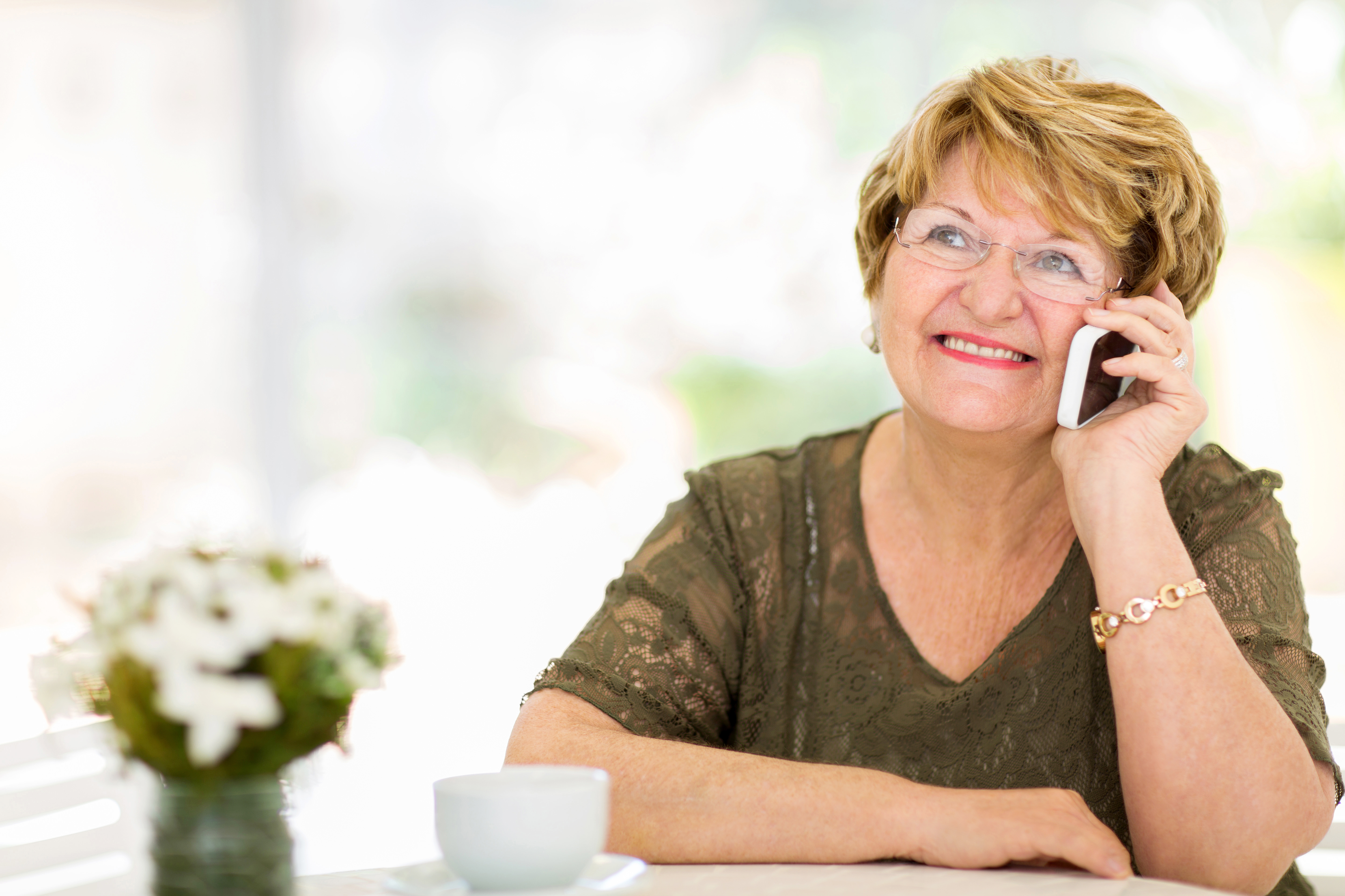 A closeup of a lady on a phone call with a cup of tea.