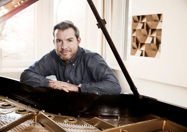 A performer leaning against a grand piano