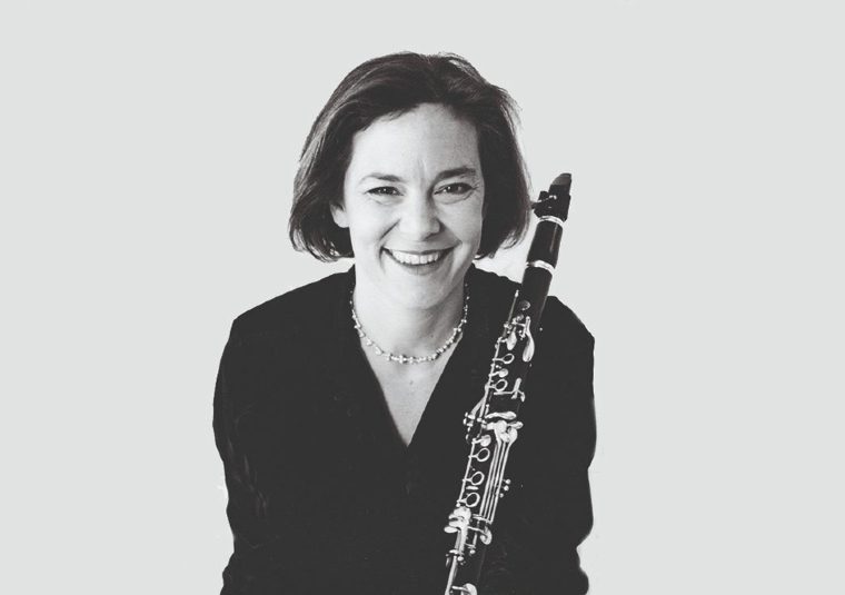 The performer looking at the camera and holding an instrument