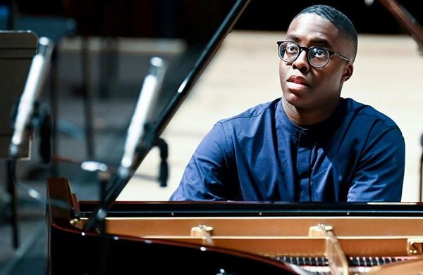The performer playing the piano and facing the camera