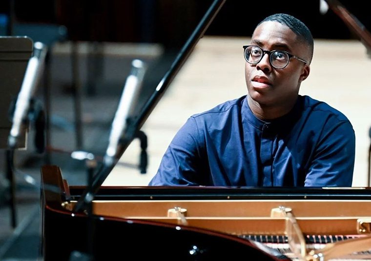 The performer playing the piano and facing the camera