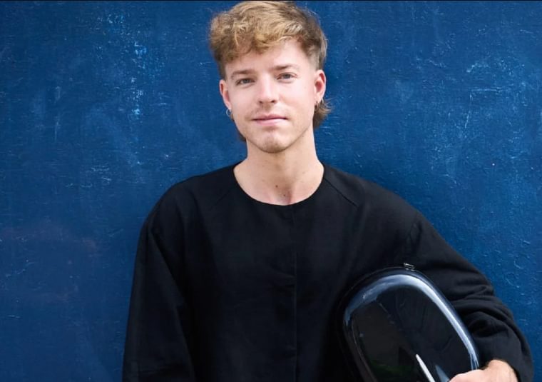 The performer holding his instrument against a blue background