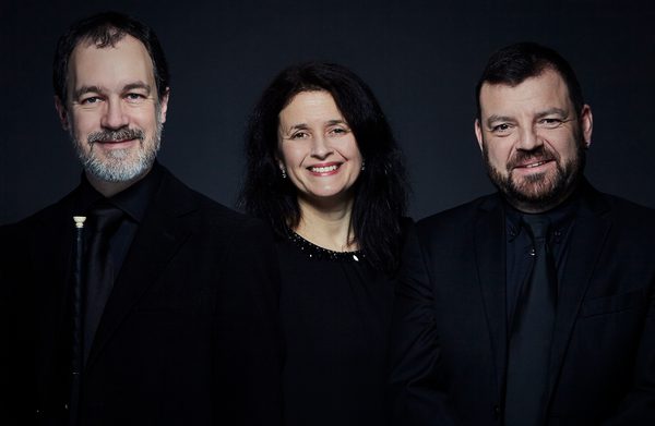 The performers looking at the camera against a dark background