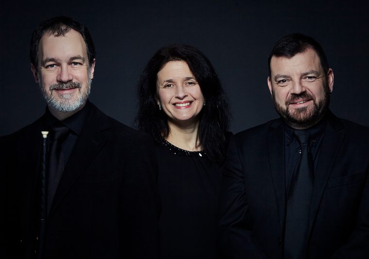 The performers looking at the camera against a dark background