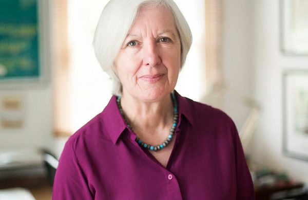 The speaker, in an office, looking at the camera