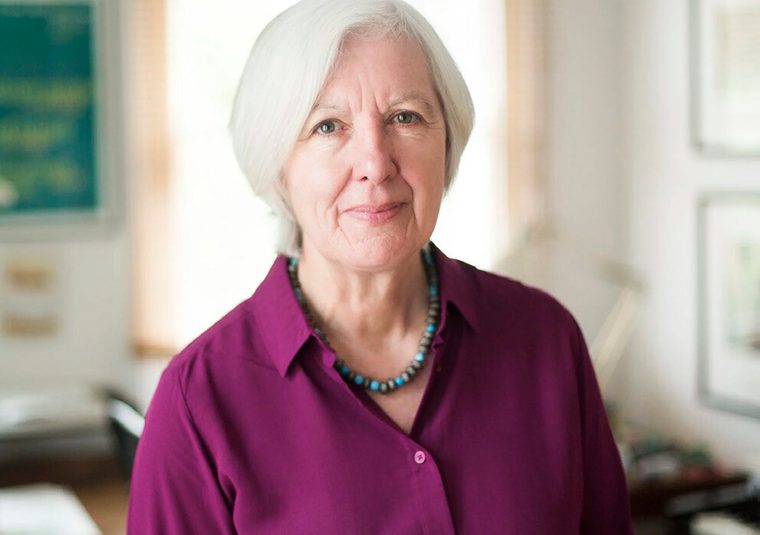 The speaker, in an office, looking at the camera