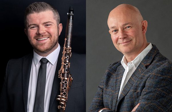 The performers standing against a gray background, facing the camera