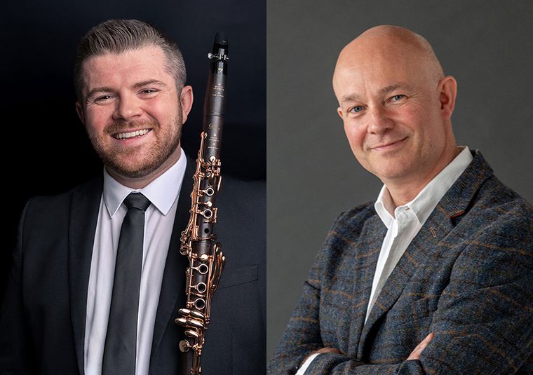 The performers standing against a gray background, facing the camera