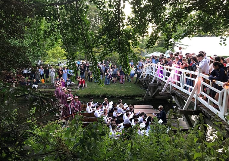 An audience gathered on a bridge and a river bank