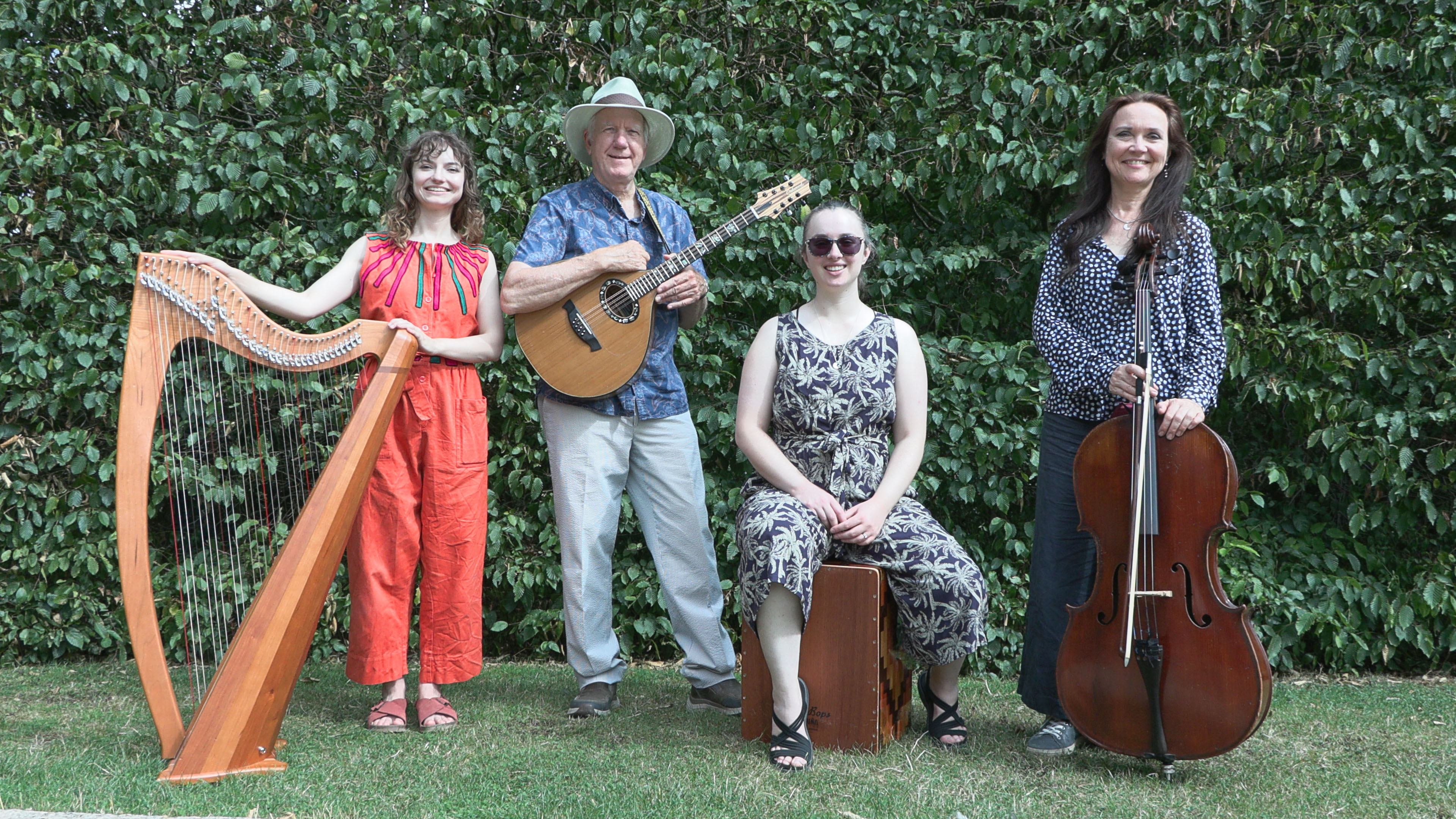 The performers, holding their instruments, and pictured in a green space