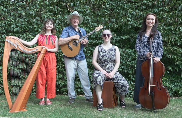 The performers, holding their instruments, and pictured in a green space