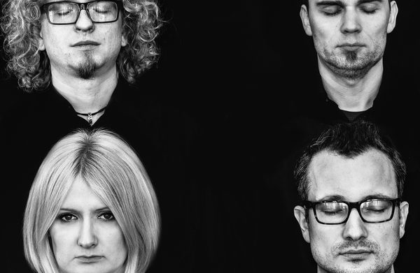 Four performers looking at camera against a black background