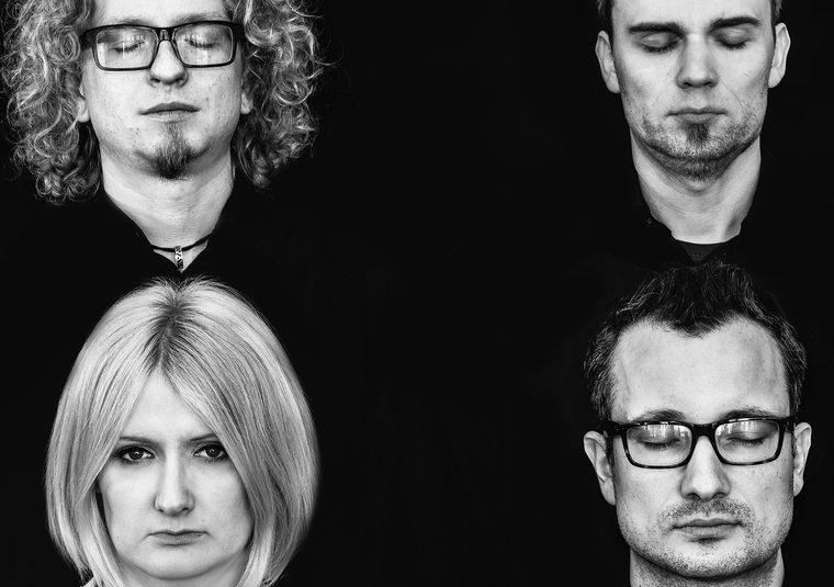 Four performers looking at camera against a black background