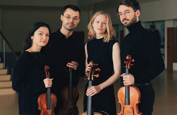 The performers, in front of a staircase, with instruments