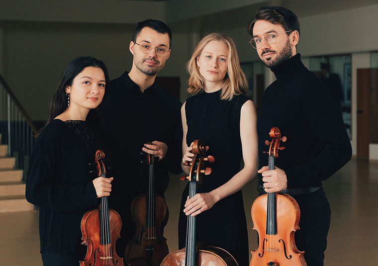 The performers, in front of a staircase, with instruments