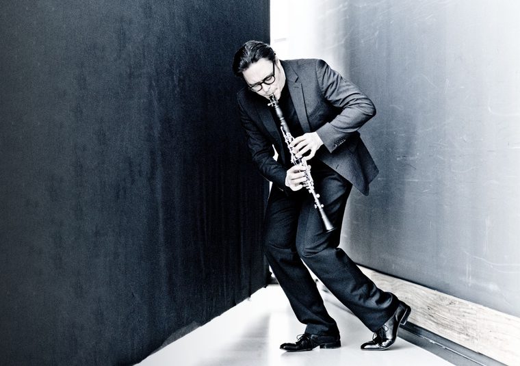 The performer playing an instrument in a black and white room