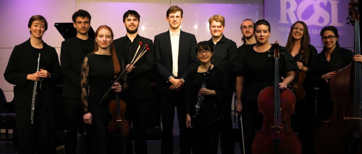 The performers, holding their instruments, and depicted in front of a white and purple backdrop