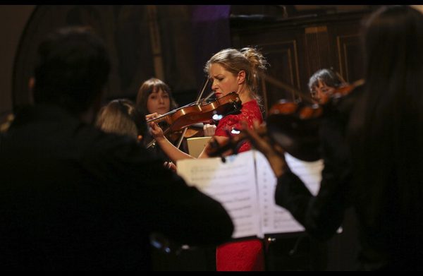 A performer playing an instrument surrounded by an orchestra