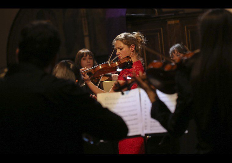 A performer playing an instrument surrounded by an orchestra