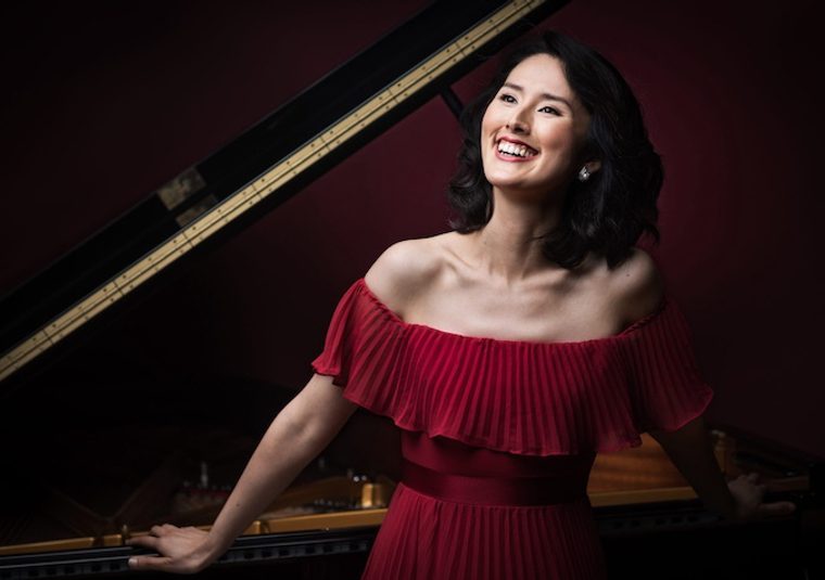 The performer standing beside a grand piano