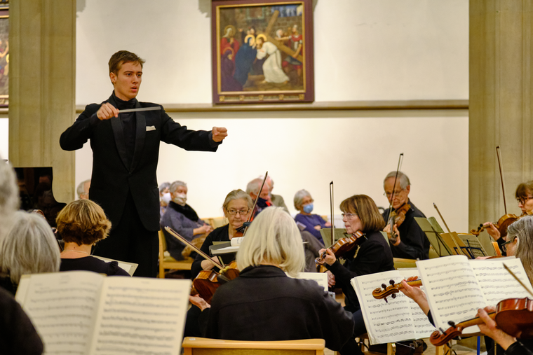 A conductor conducting an orchestra in a venue
